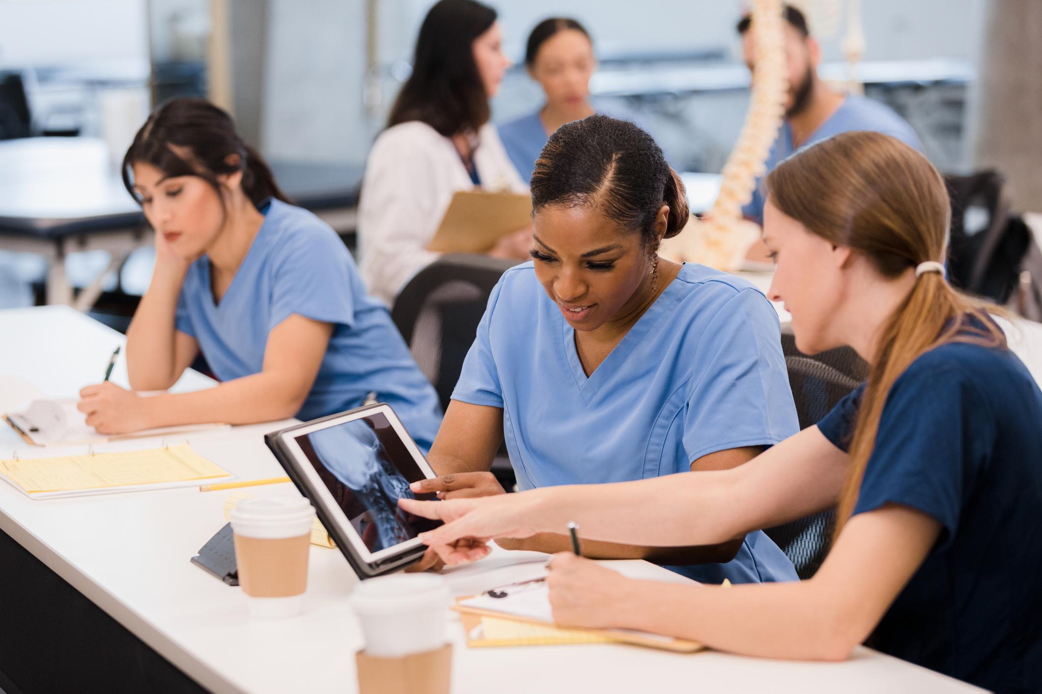 nurse talking to another nurse while showing tablet